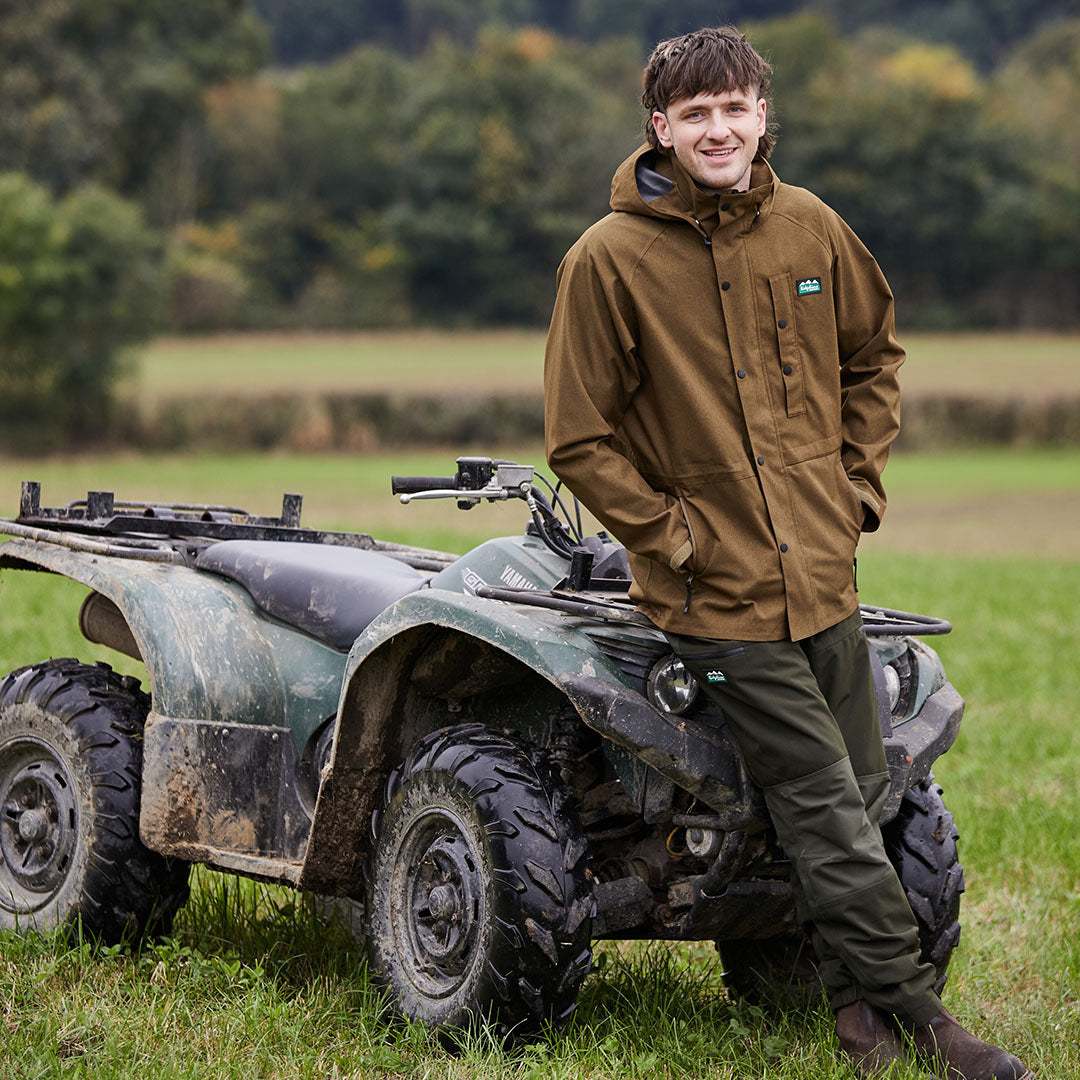 Muddy green Yamaha ATV with Ridgeline Monsoon Light Jacket in outdoor adventure setting