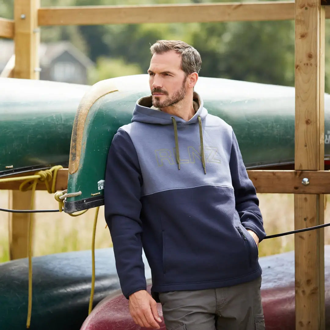 Man in two-tone South Island hoodie next to a canoe, enjoying the great outdoors