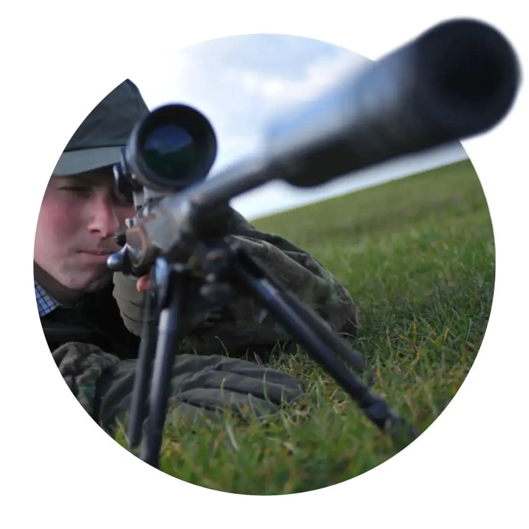 Sniper rifle on grass next to Sealskinz Broome Shooting Glove for hunting and country clothing