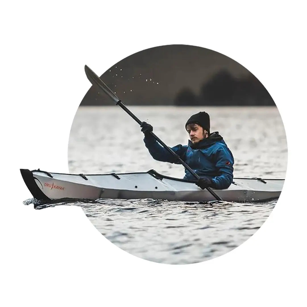 Kayaker in a white kayak wearing a Sealskinz Cley Hat on calm water