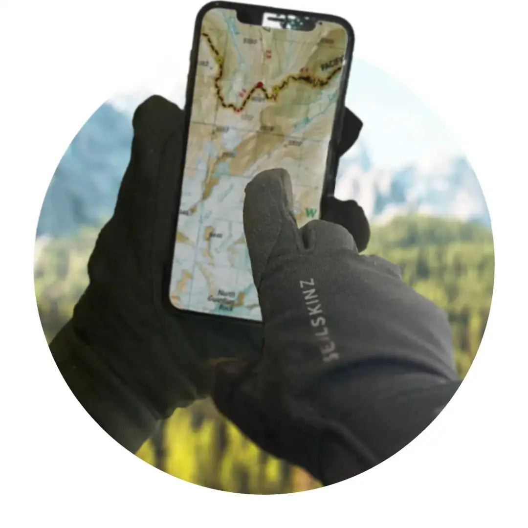 Smartphone with a topographic map in a gloved hand, perfect for country clothing adventures