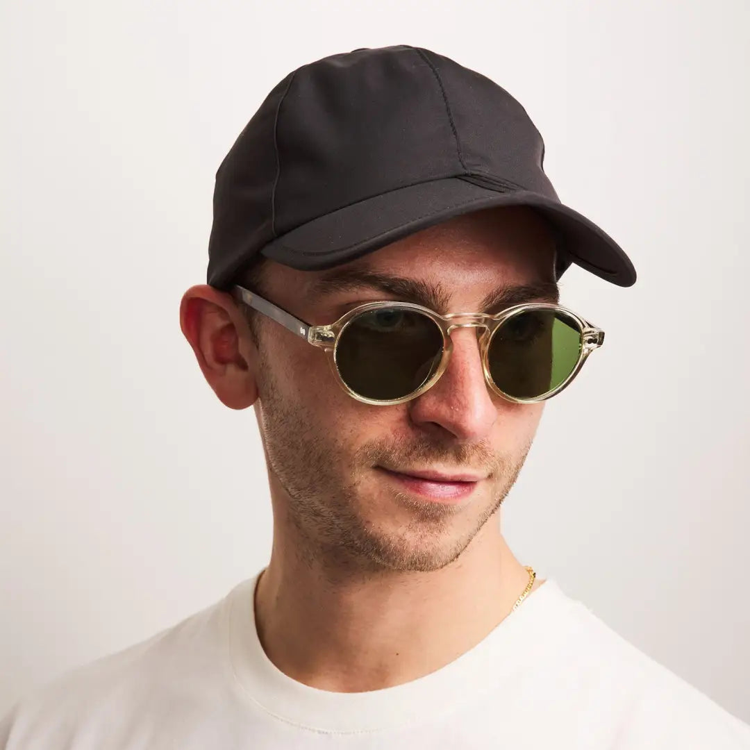 Person in a black Salle Cap and green sunglasses, perfect for country clothing and hunting