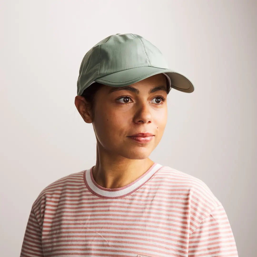 Person sporting a light green Sealskinz Salle Cap and a pink striped shirt