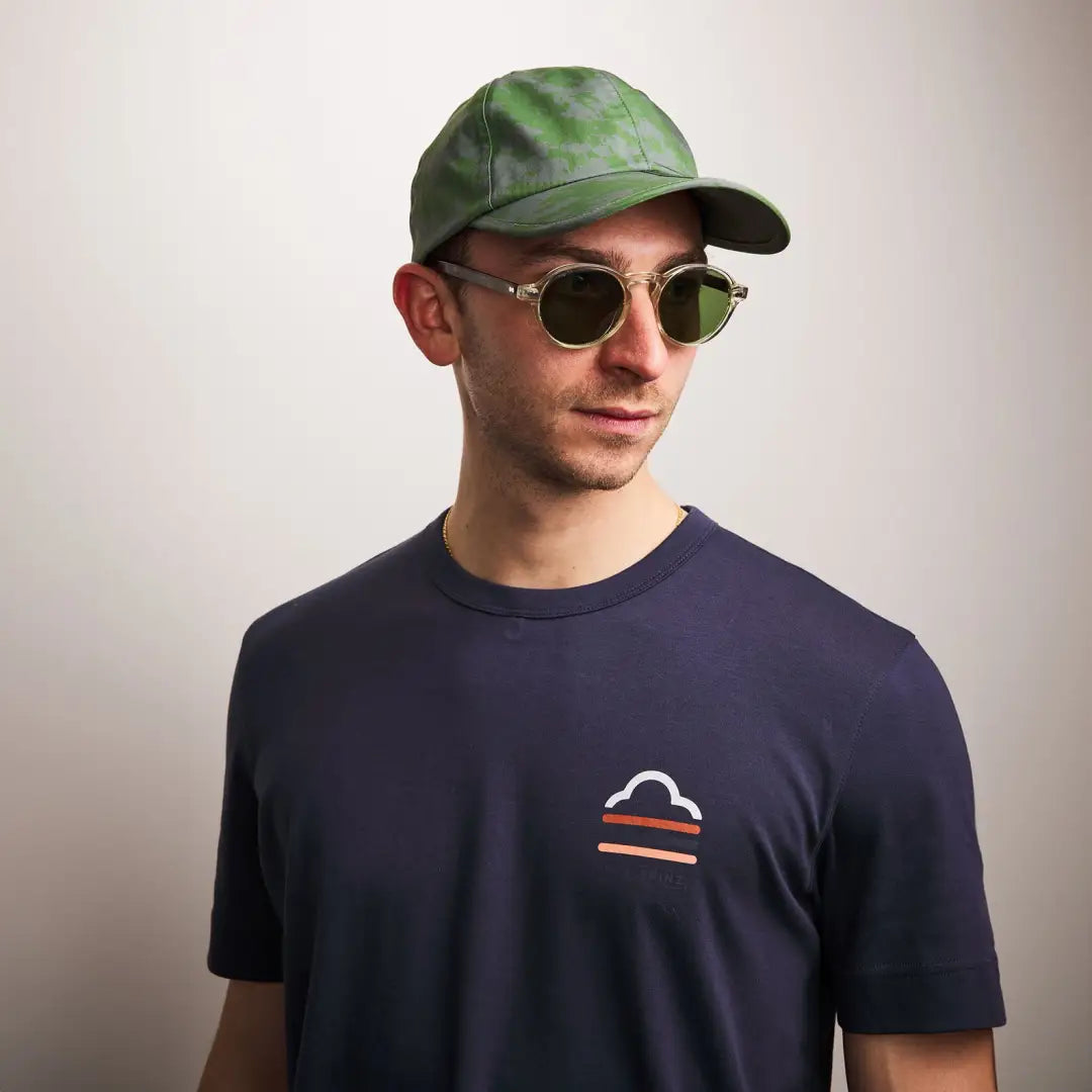 Man in green baseball cap, sunglasses, and navy t-shirt, showcasing Sealskinz Salle Skinz Cap for outdoors