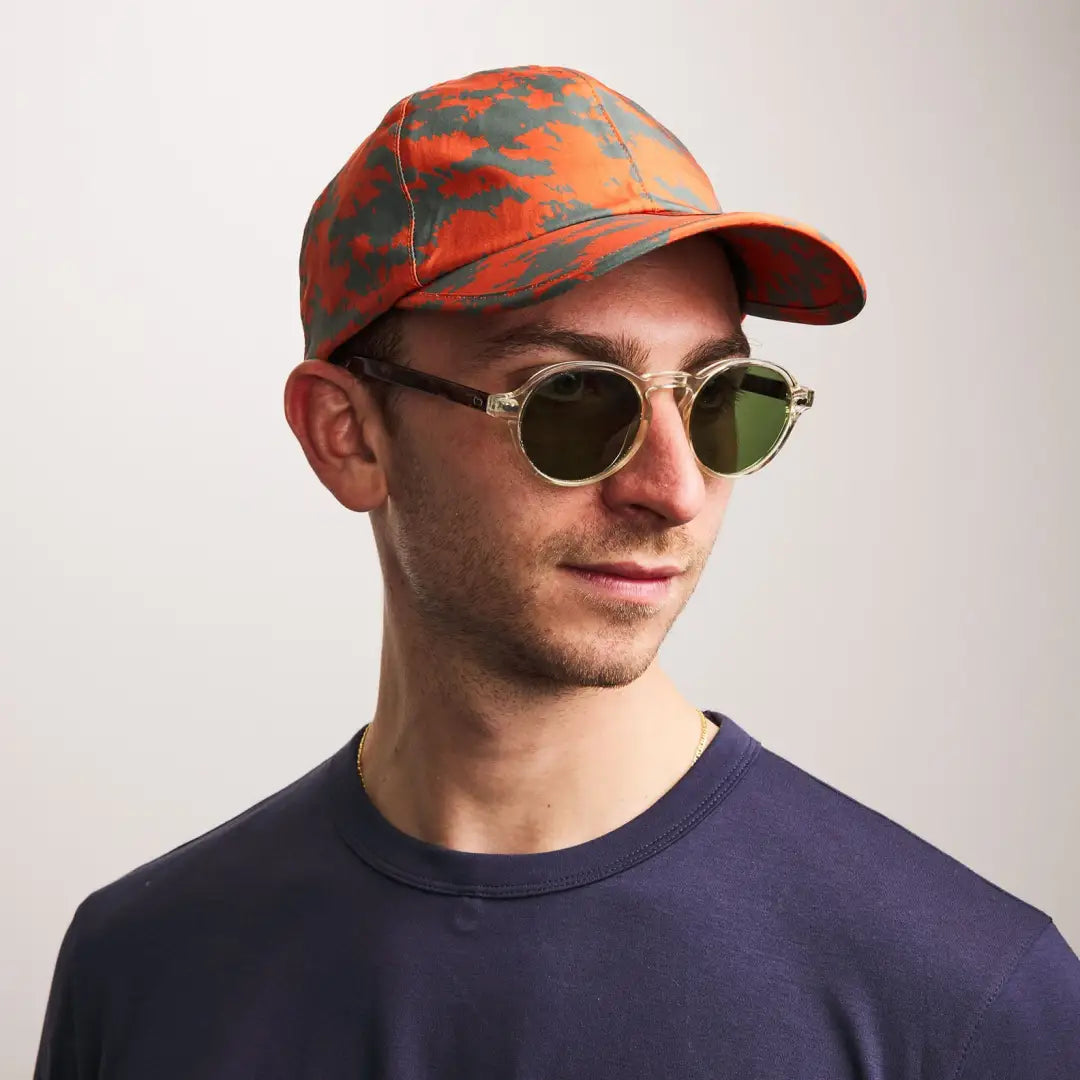 Person rocking a colorful Sealskinz Salle Skinz Cap and round sunglasses