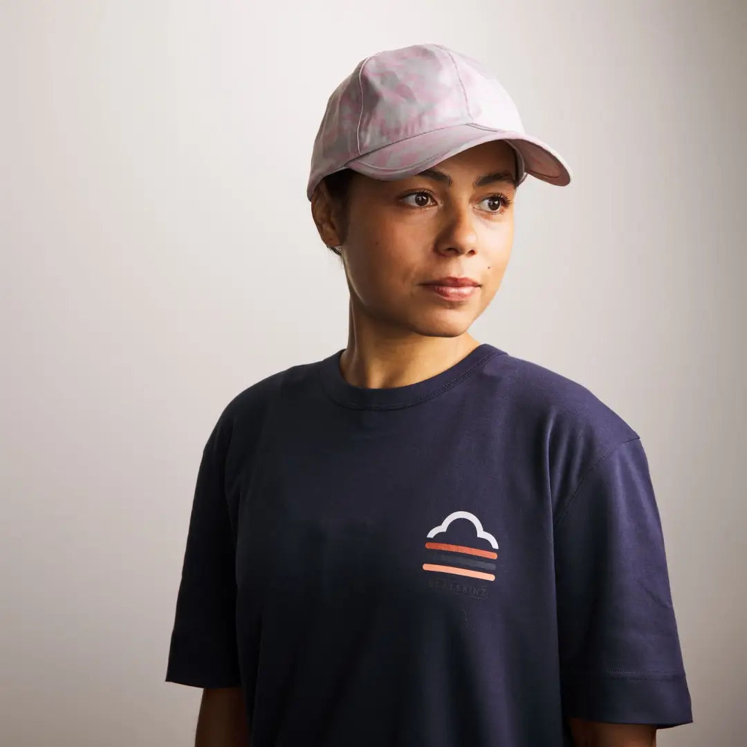 Person in navy t-shirt and light pink baseball cap enjoying Sealskinz Salle Skinz Cap outdoors