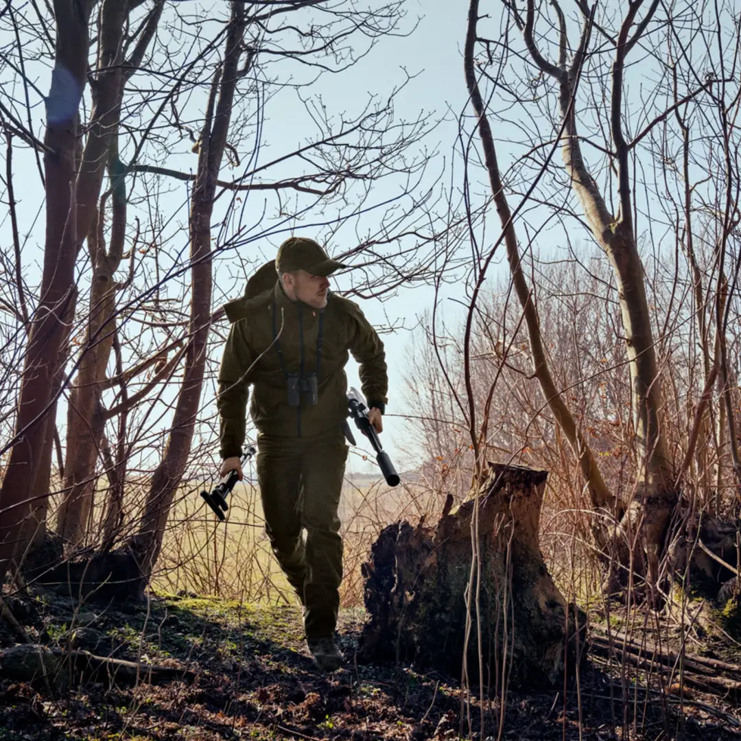 Hunter in a leafless forest wearing a Seeland Avail Jacket and carrying a rifle