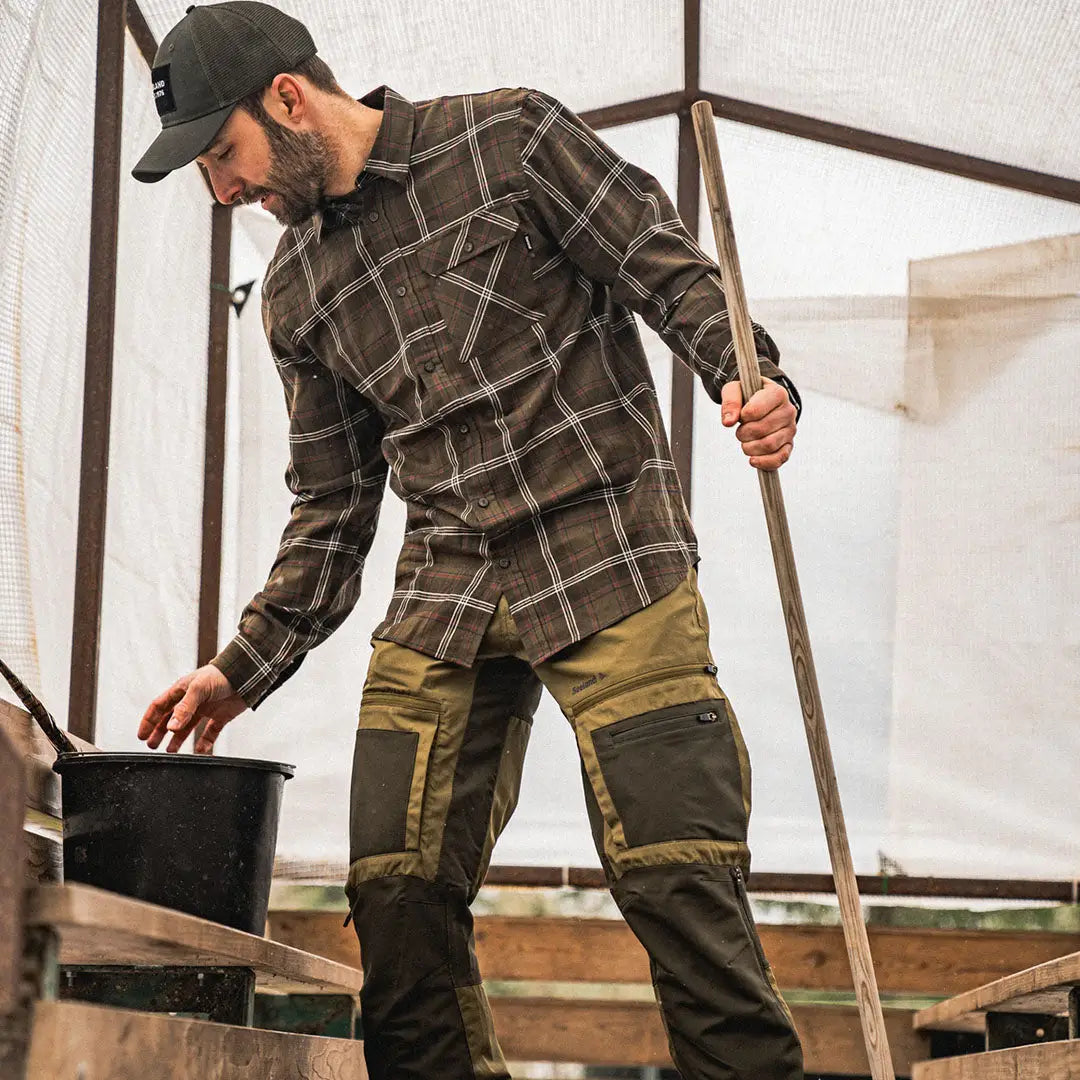 Man in a Seeland Glen Flannel shirt and cargo pants working with a tool and bucket