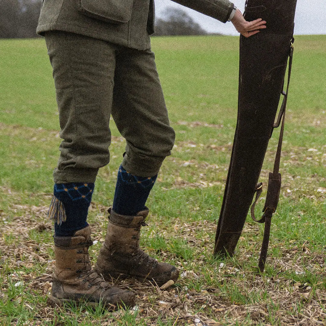 Muddy boots with a hunting rifle in a field, perfect for Seeland Harriet Breeks