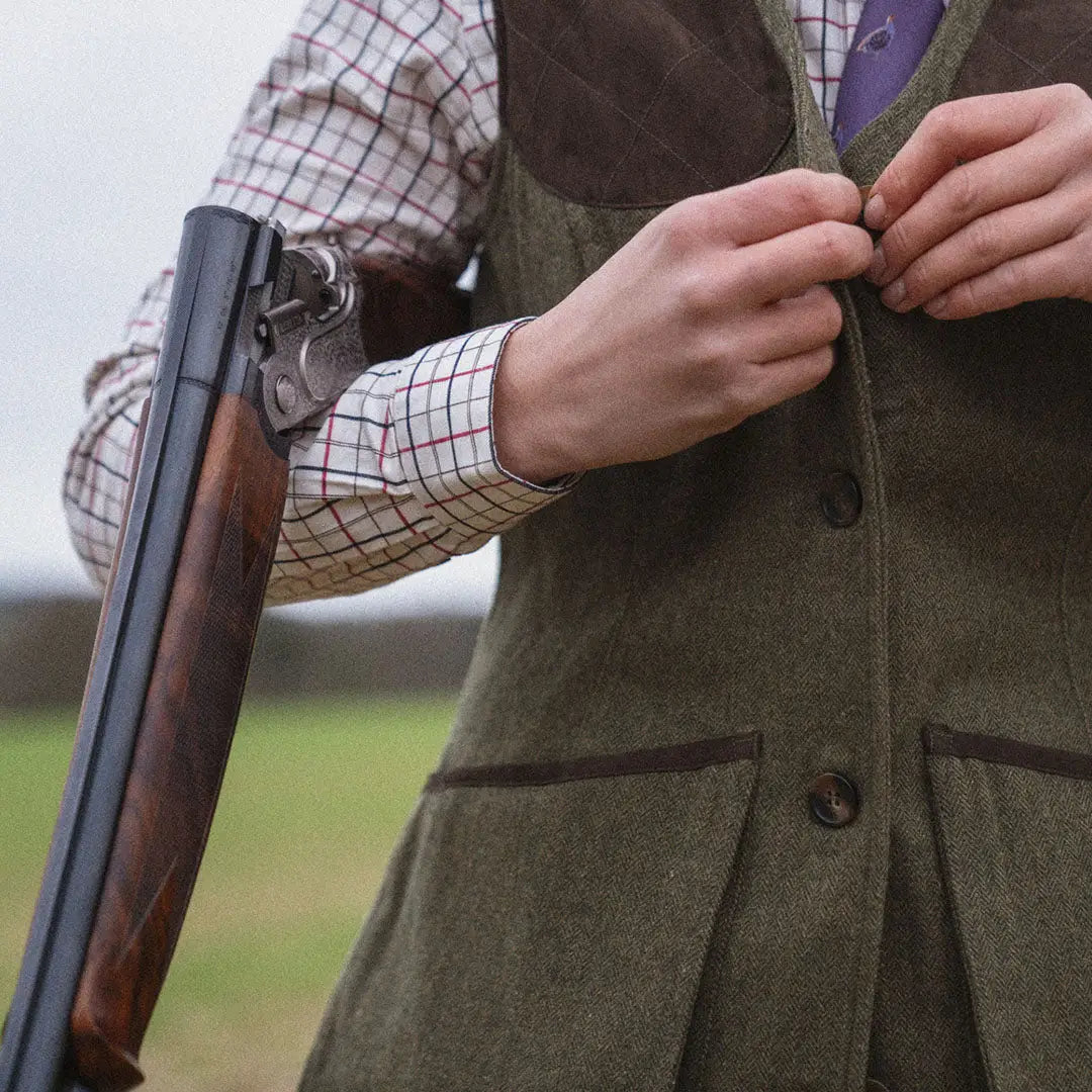 Person in plaid shirt and green vest holds shotgun with Seeland Hillside Harriet Waistcoat