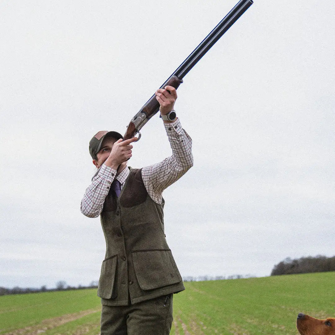 Person in Seeland Hillside Harriet Waistcoat aiming a shotgun skyward