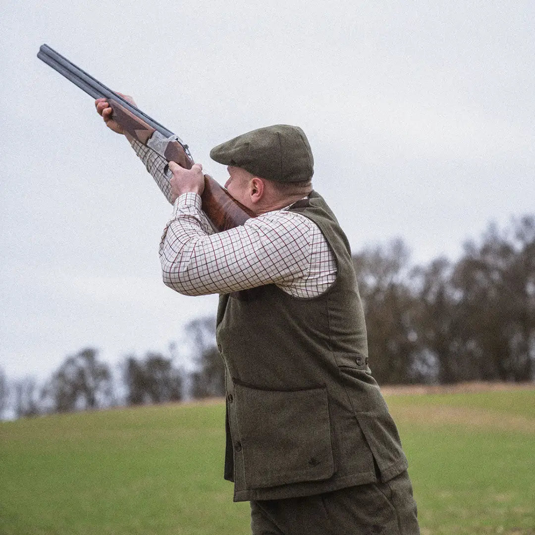 Man in traditional hunting gear aiming a shotgun with Seeland Hillside Waistcoat