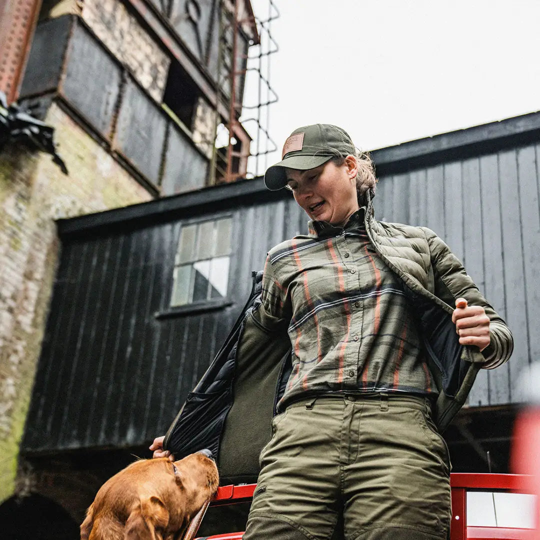 Woman in Seeland Skye country clothing playing with a brown dog outdoors