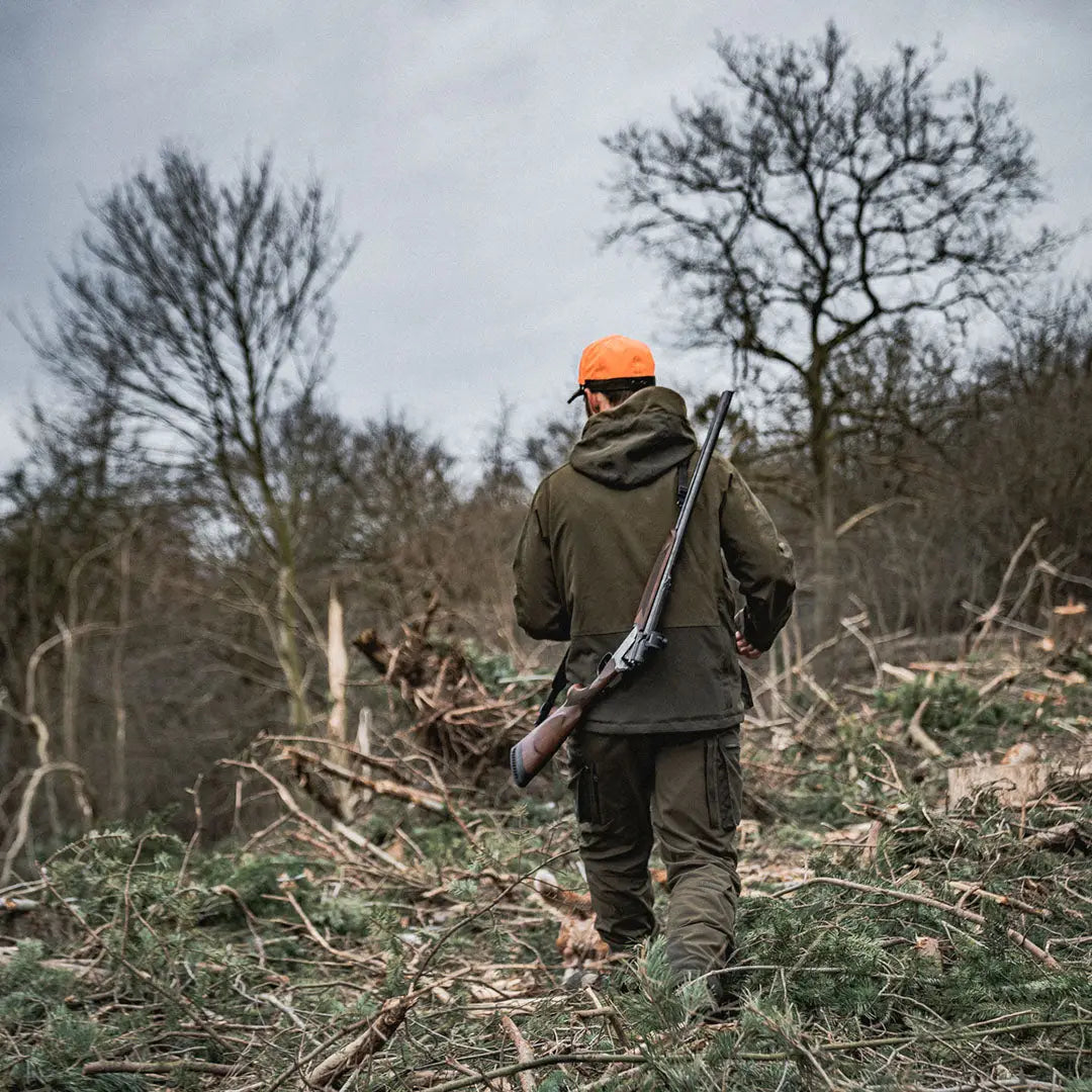 Hunter in Seeland Trax Jacket, wearing camo and an orange hat in the forest