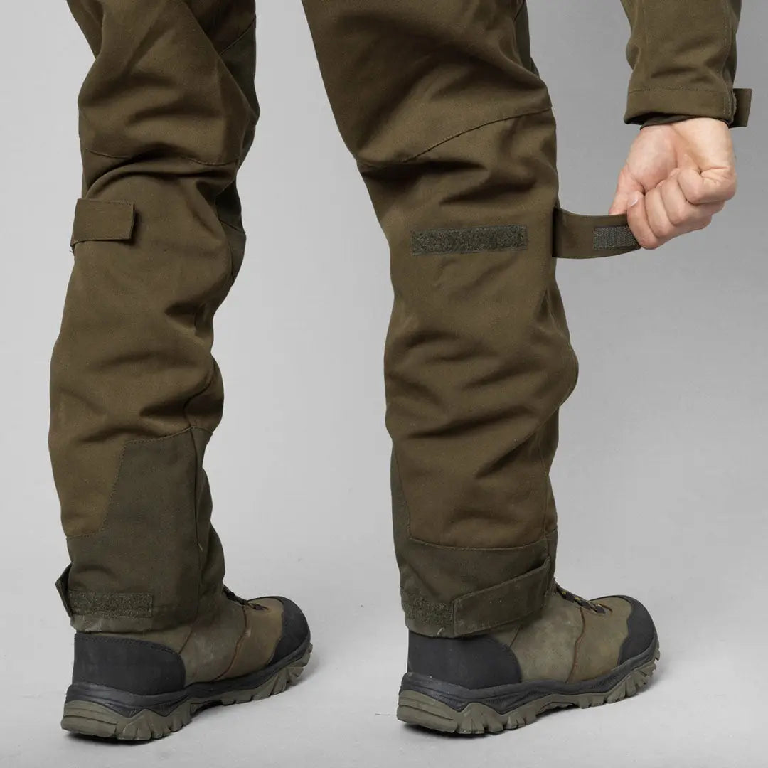 Pair of olive green Seeland Trax Trousers with rugged boots for country clothing and hunting