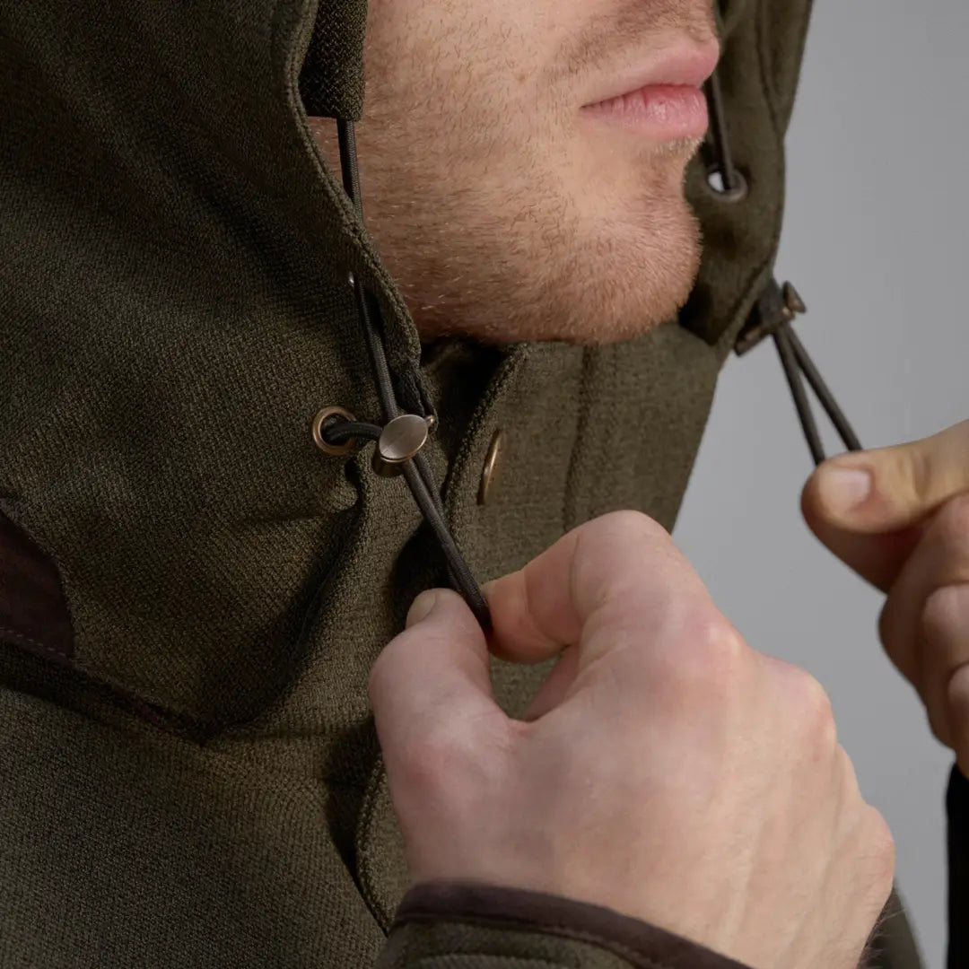 Olive green hooded Seeland Woodcock Advanced Jacket being zipped up with stretch material