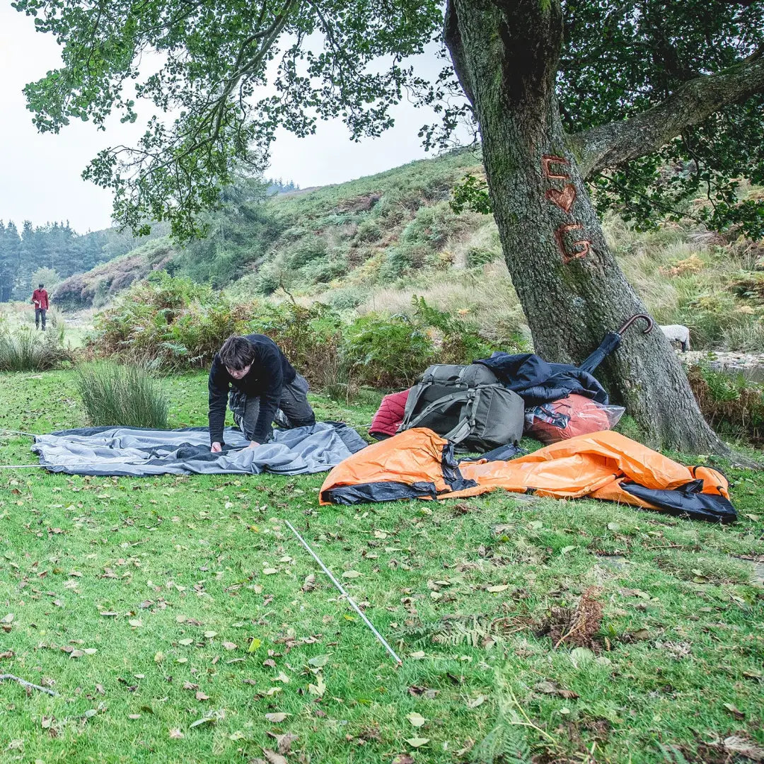 Campsite with sleeping bags and gear under a tree featuring the Bergen Rucksack