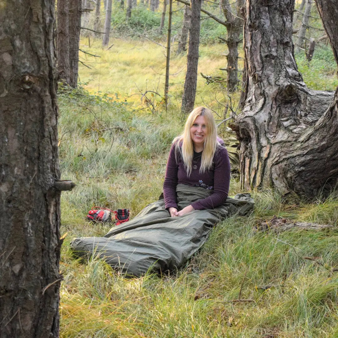 Person relaxing inside a Snugpak Bivvi Bag on the forest floor, showcasing its lightweight design