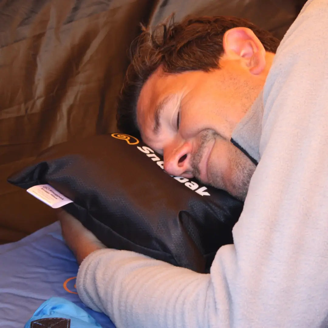 Person snoozing with a black Snugpak Snuggy Headrest pillow, perfect for outdoors and hunting