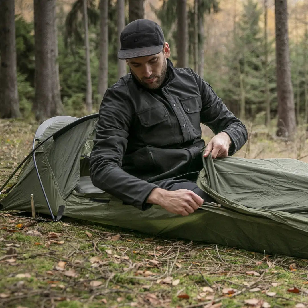 Green camping tent set up in a forest, showcasing the Snugpak Stratosphere bivvi shelter