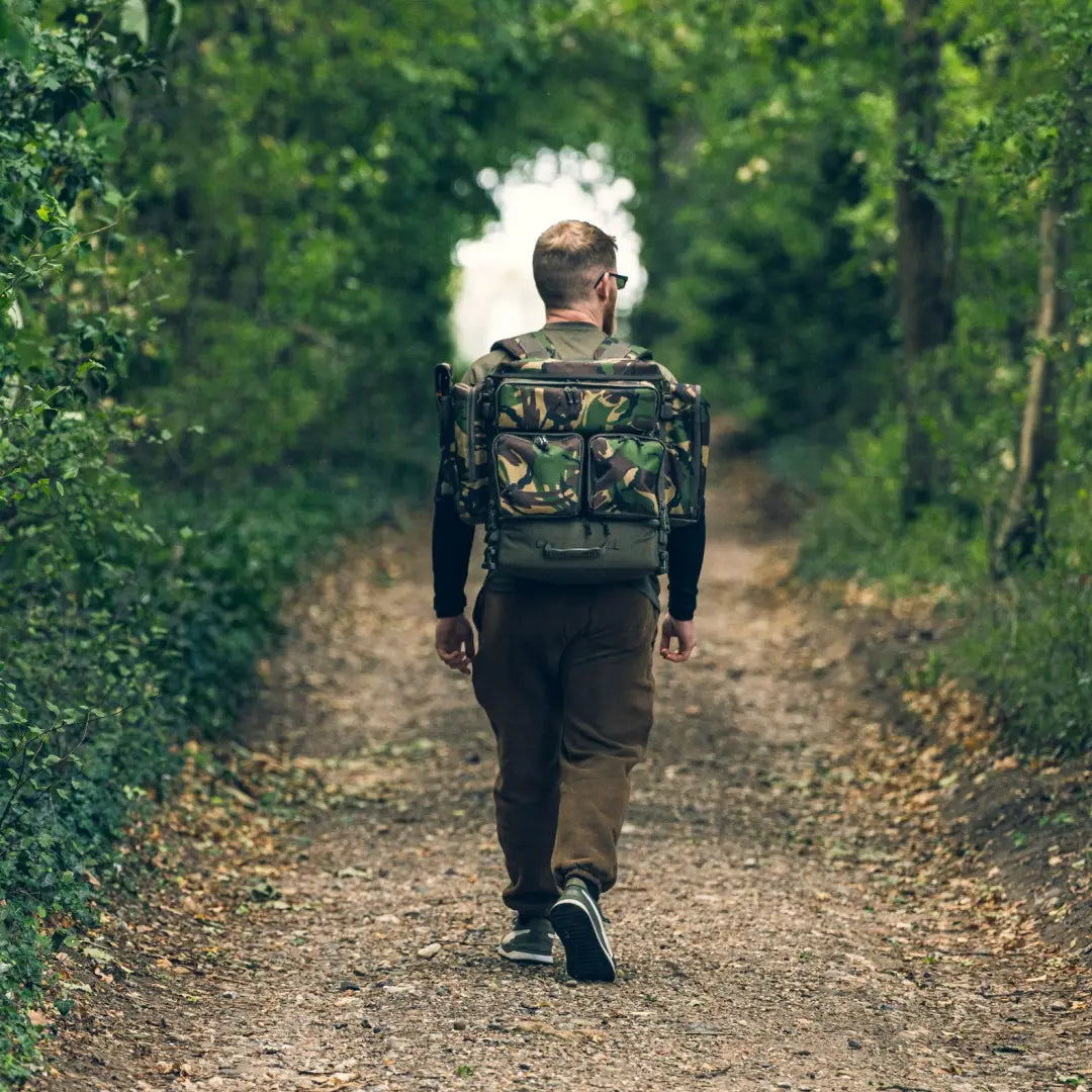 Person hiking on a forest path with a Speero Compact Rucksack in camouflage design