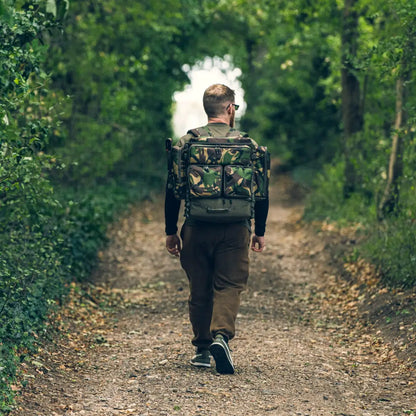 Person hiking on a forest path with a Speero Compact Rucksack in camouflage design