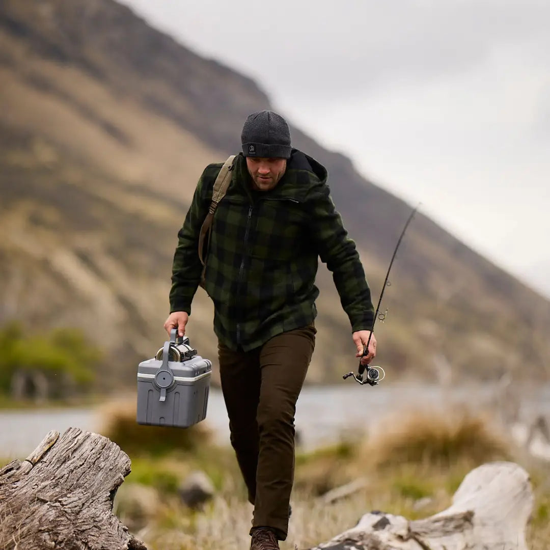 Fisherman in Hudson Wool Hoody carrying tackle box and rod on rocky terrain