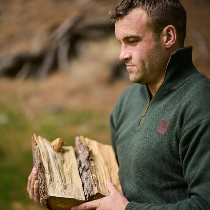 Man in Swanndri Mariner Zip Neck Jumper holding split firewood logs outdoors