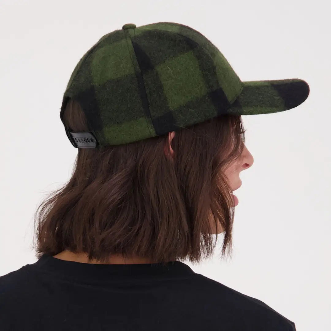 Person with brown hair wearing a green and black checkered Swanni Wool Baseball Cap