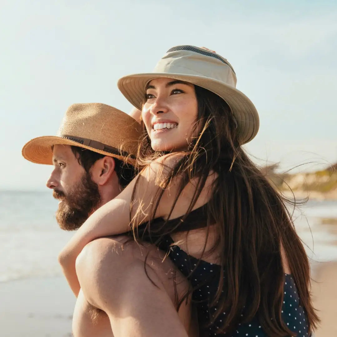 Smiling woman in a sun hat and polka dot top enjoying the beach with her Tilley Airflo Hat