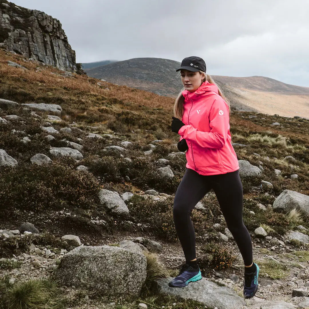 Runner in a bright pink Venture Ultralight jacket tackling rocky terrain