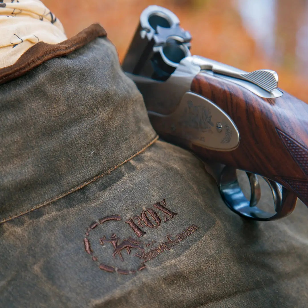 Weathered canvas bag with Fox logo beside a shotgun from the Fox Original Jacket