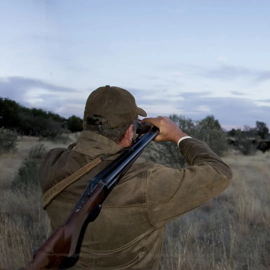 Hunter aiming a shotgun in a field wearing the Fox Original Jacket