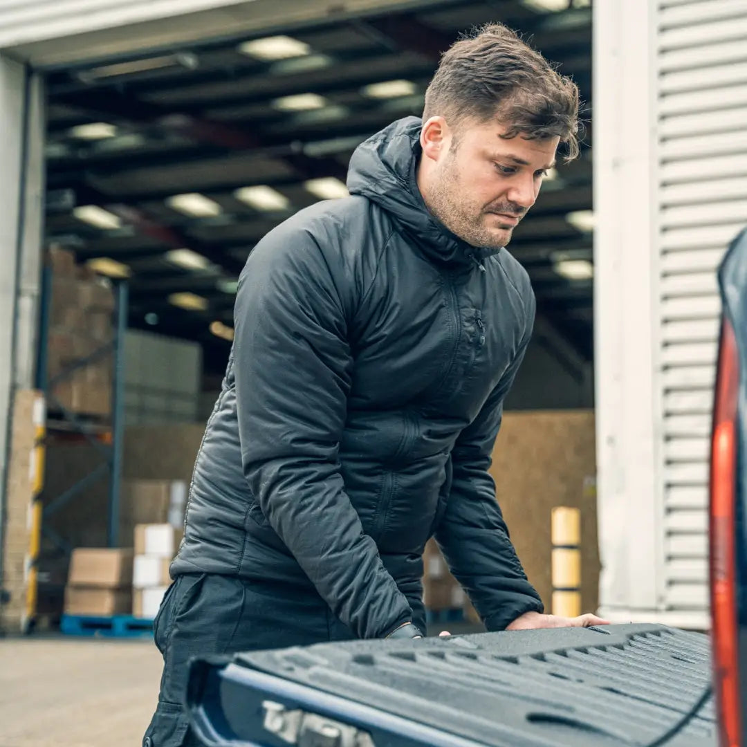 Man in a dark jacket handling gear, showcasing the Viper Tactical Frontier Jacket