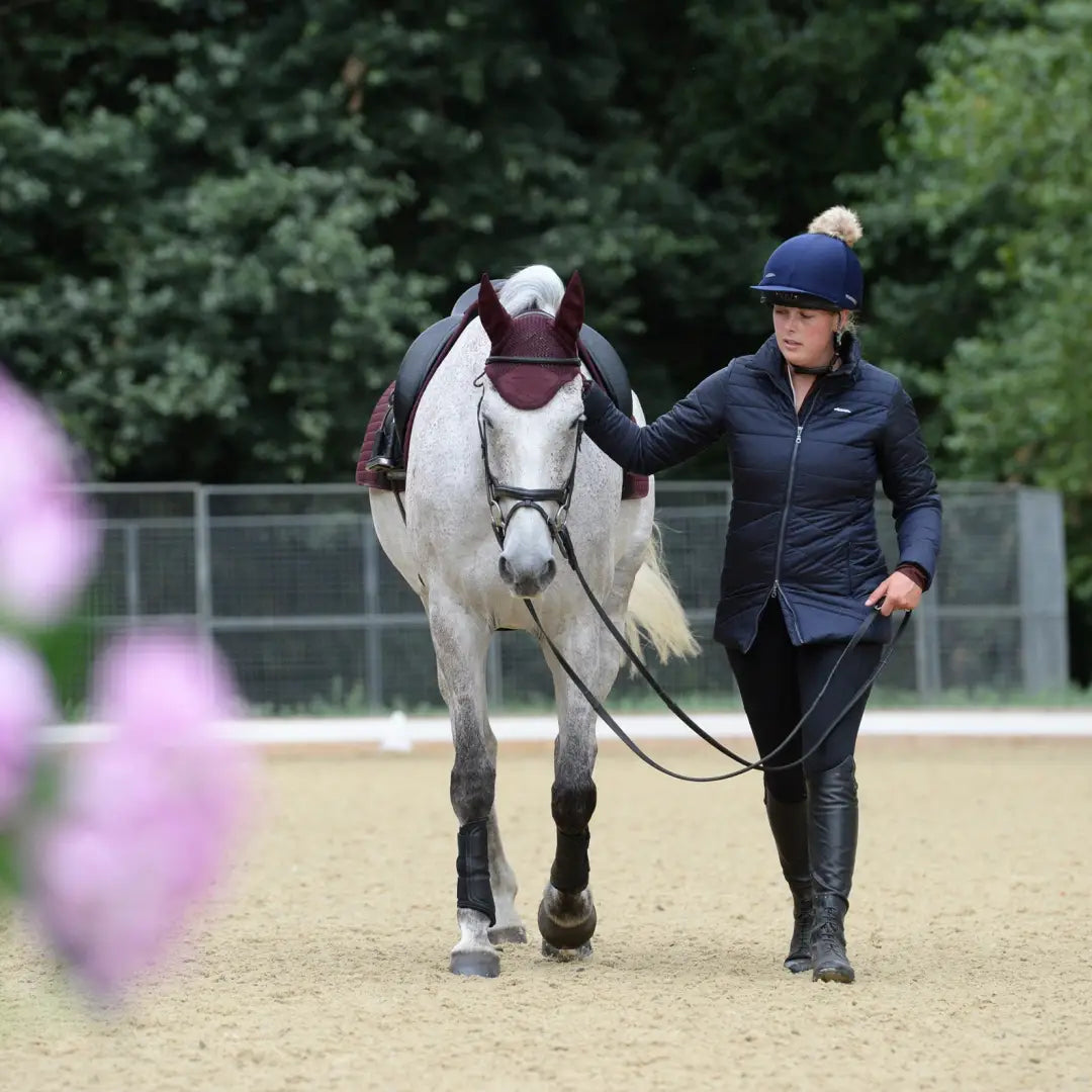 Rider in equestrian gear leading horse while wearing WeatherBeeta Harlow Puffer Jacket