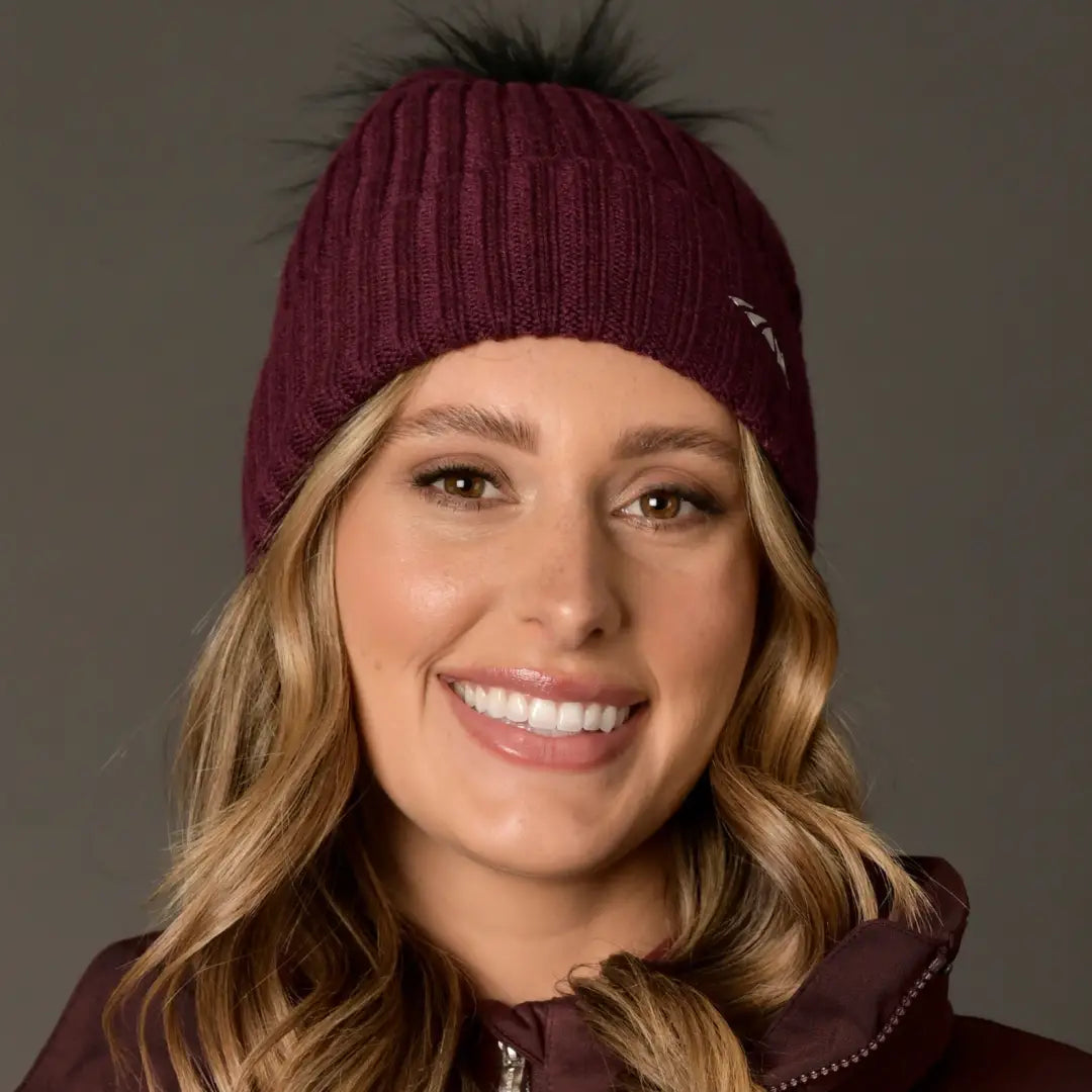 Smiling woman models a WeatherBeeta Knit Beanie in stylish burgundy color